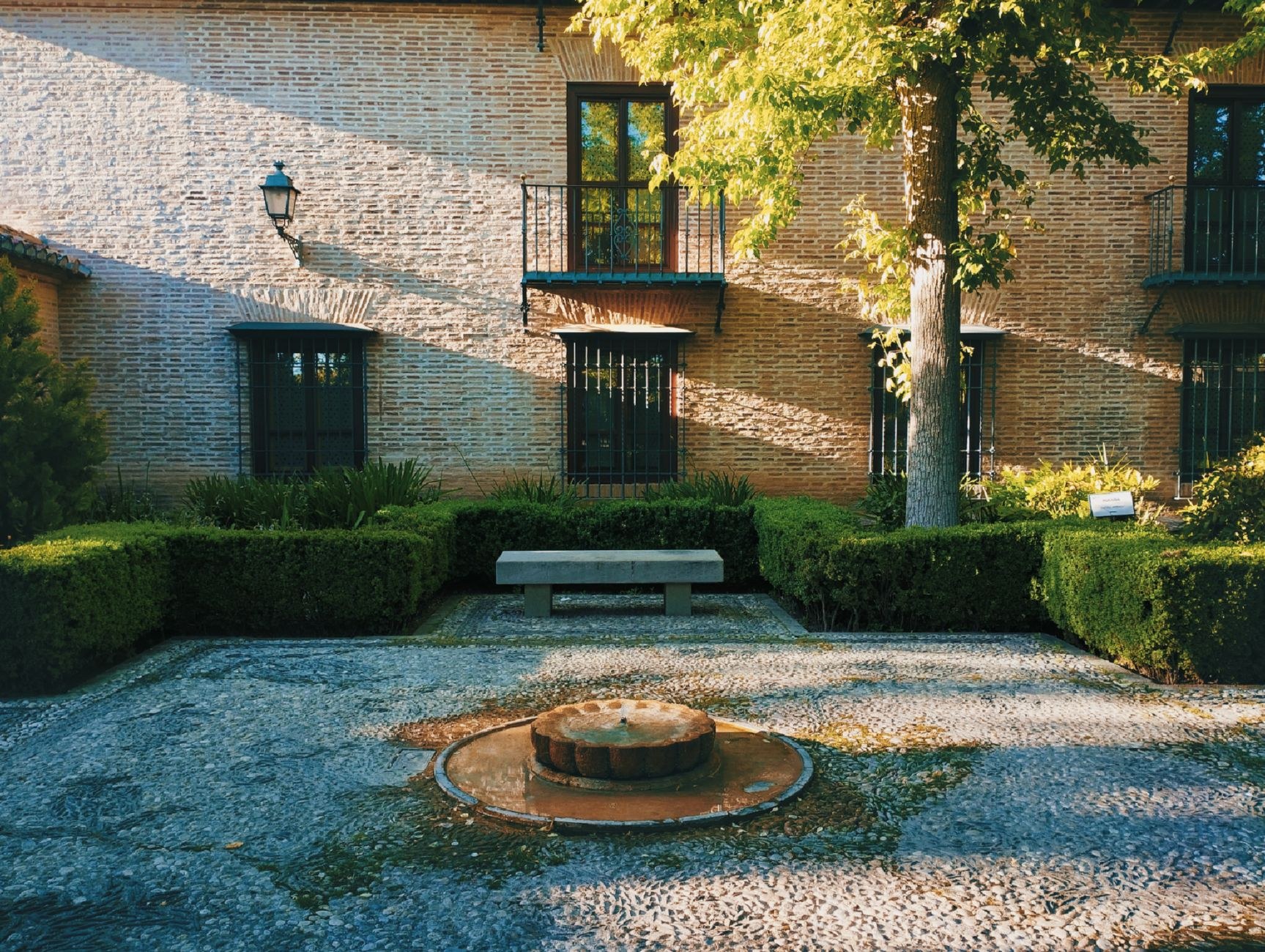 Formal courtyard garden with clipped hedges, a central water feature and gravel paths